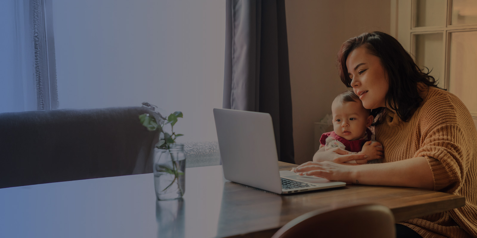 Mother and child sit at a table and look at their wi-fi computer connected to wi-fi.