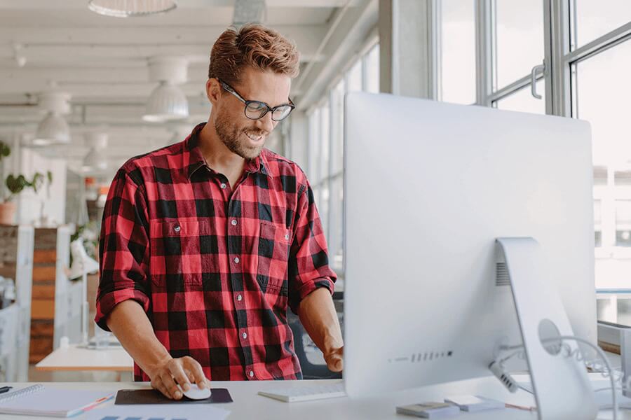 Man stands at his desk computer in a office.