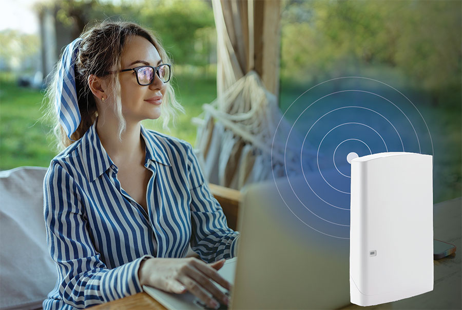 Woman sits outside using her laptop. A router with signal waves is layered on top of picture.