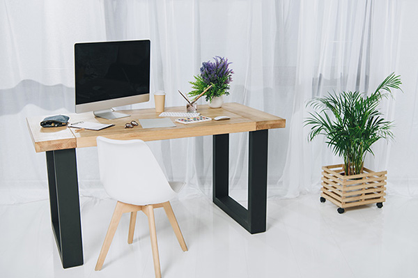 desk at an office with a large screen and plants around the desk.